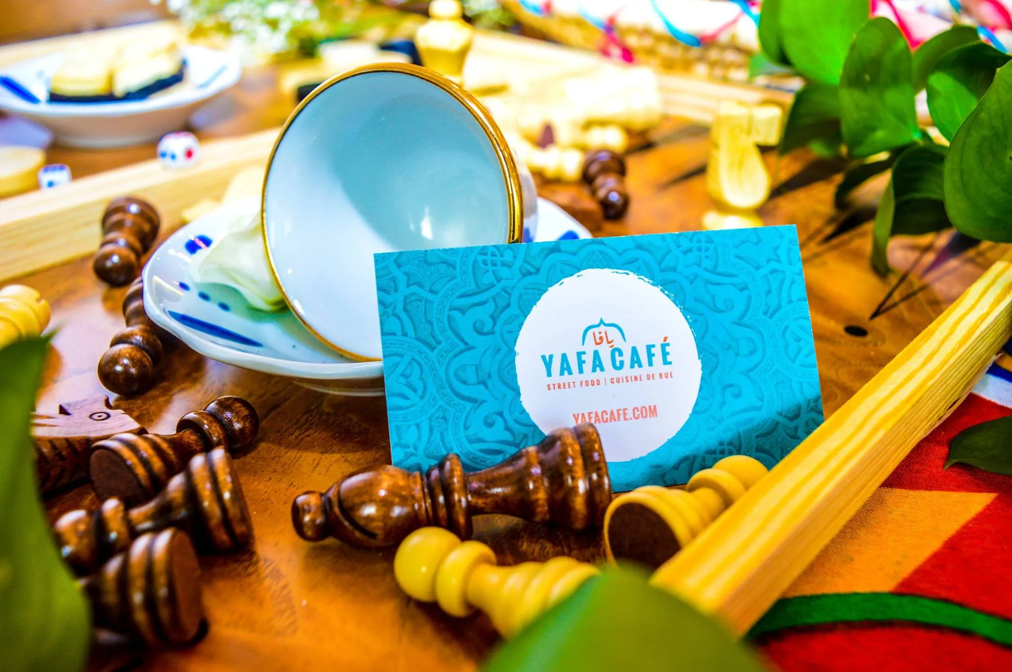 Yafa Café business card beside Arabic coffee and backgammon at the café in Winnipeg, MB